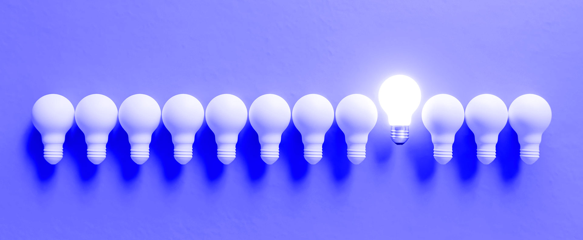 Row of lightbulbs with one lit — standing out